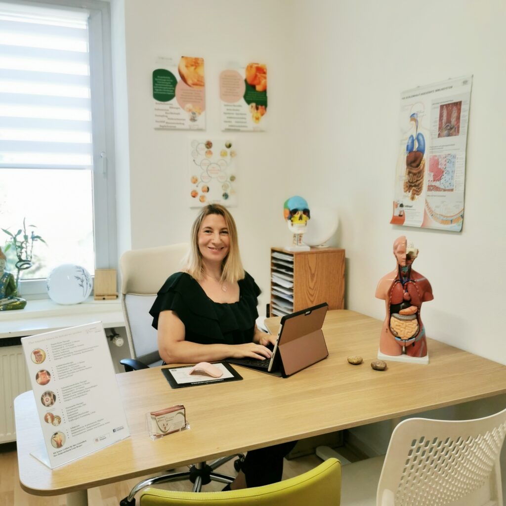 Heilpraktikerin Lena Brauer am Schreibtisch in ihrer Naturheilpraxis in München